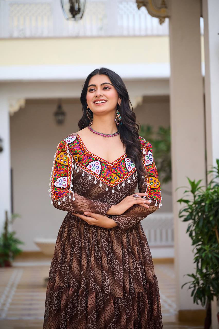 Woman smiling in brown Bandhni Gamathi work gown, featuring ornate mirror work neckline.