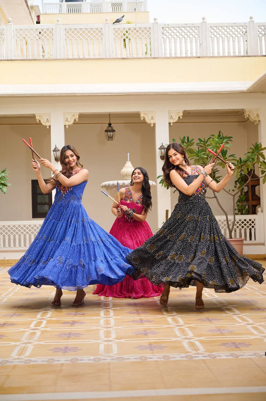 Group dancing in blue, pink, and black Bandhani gowns with mirror, codi, and cowrie work.