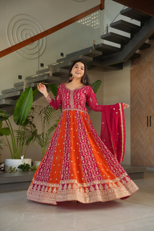 Woman in vibrant pink and orange zari embroidered gown and dupatta.