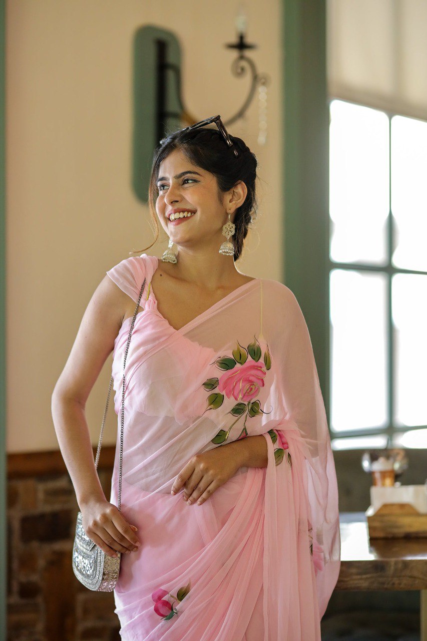 Close-up of hand-painted rose design on pink georgette saree.
