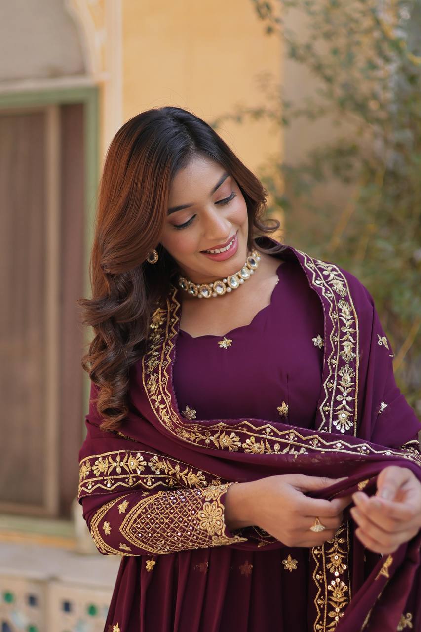 Two models wearing plum and teal Anarkali gowns with gold embroidery.