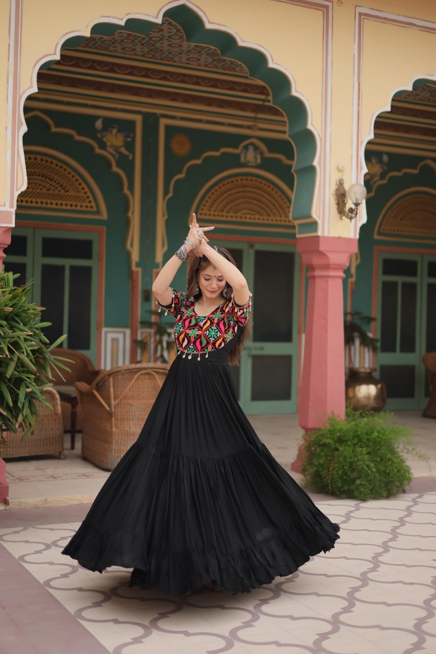 Woman twirling in black Kutchi work Navratri gown, showing voluminous skirt and colorful bodice.