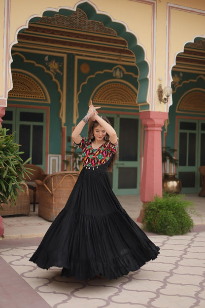 Woman twirling in black Kutchi work Navratri gown, showing voluminous skirt and colorful bodice.