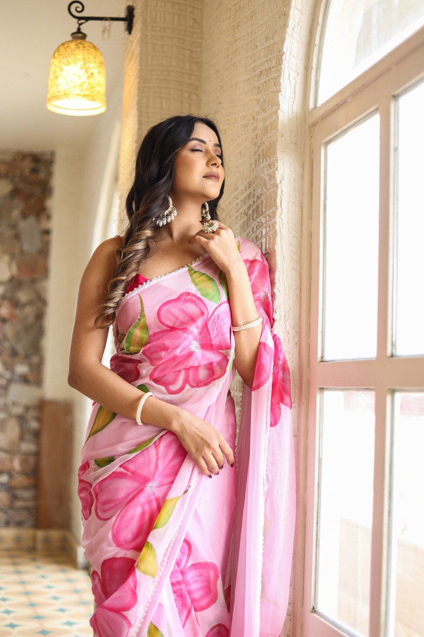 Model wearing a soft pink georgette saree with a vibrant floral design.