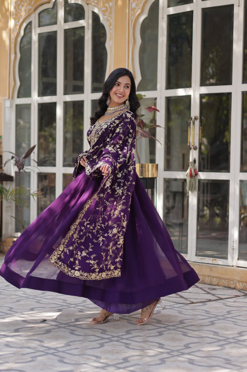 Model twirling in premium purple embroidered Indian gown with matching dupatta.