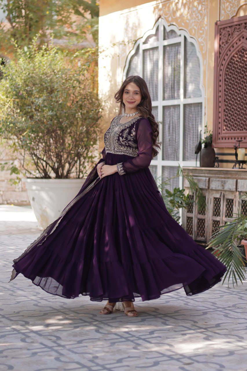 Woman twirling in a stylish purple embroidered Georgette gown.