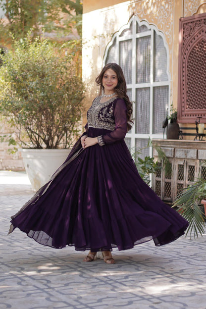 Woman twirling in a stylish purple embroidered Georgette gown.