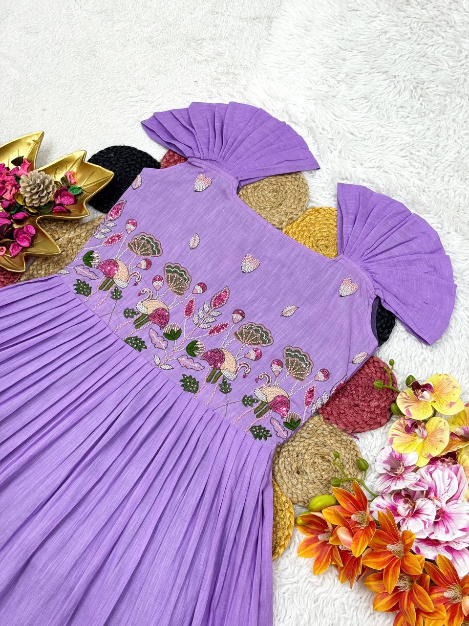 Overhead view of the purple and violet cotton gown with handwork, styled with floral accents.