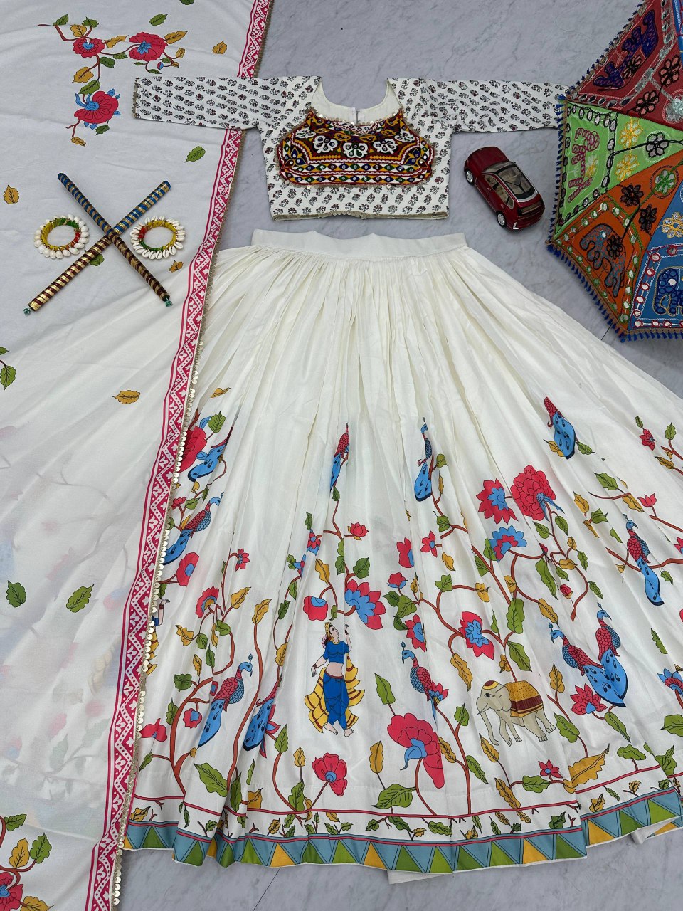 Full set of Gamthi Grace Lehenga Choli laid out, showing vibrant folk prints, blouse, dupatta, and props.