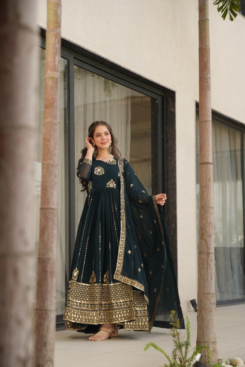 Woman in a Rama green gown with dupatta, posing near a window.