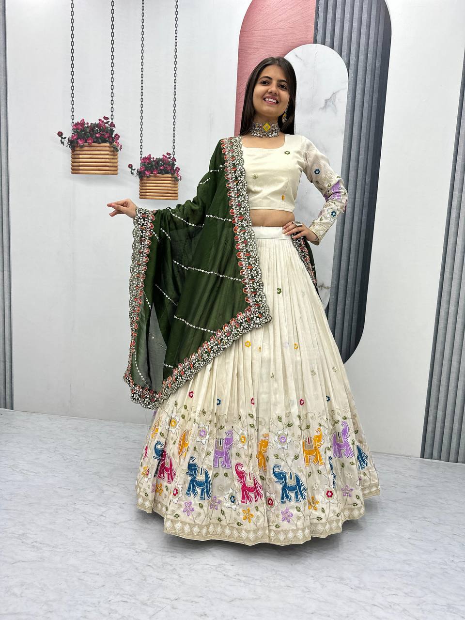 Woman in off-white lehenga choli with elephant embroidery and an olive green dupatta.