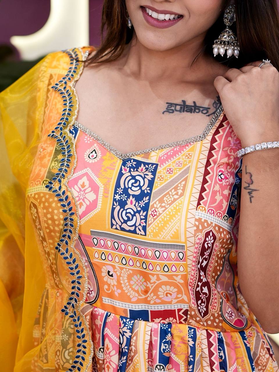 Stylish yellow Anarkali suit with colorful print and net dupatta detail.