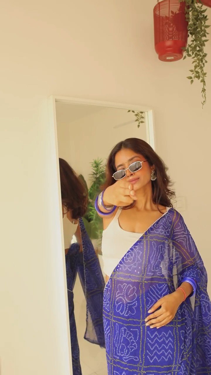 Model wearing modern blue georgette saree with sunglasses and jewelry.