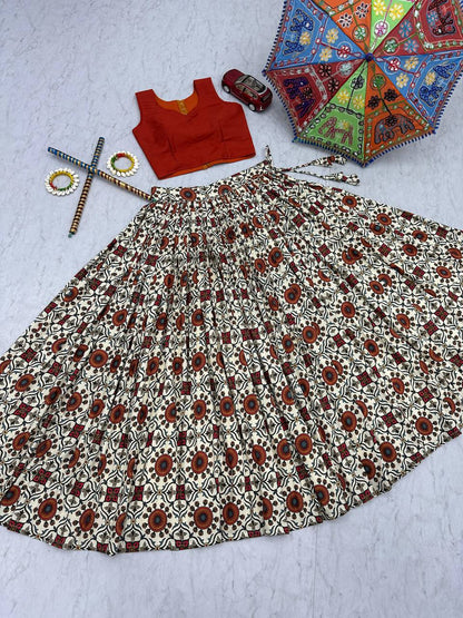 Flat lay of lehenga choli skirt and orange blouse with festive props, highlighting Kachchi embroidery.