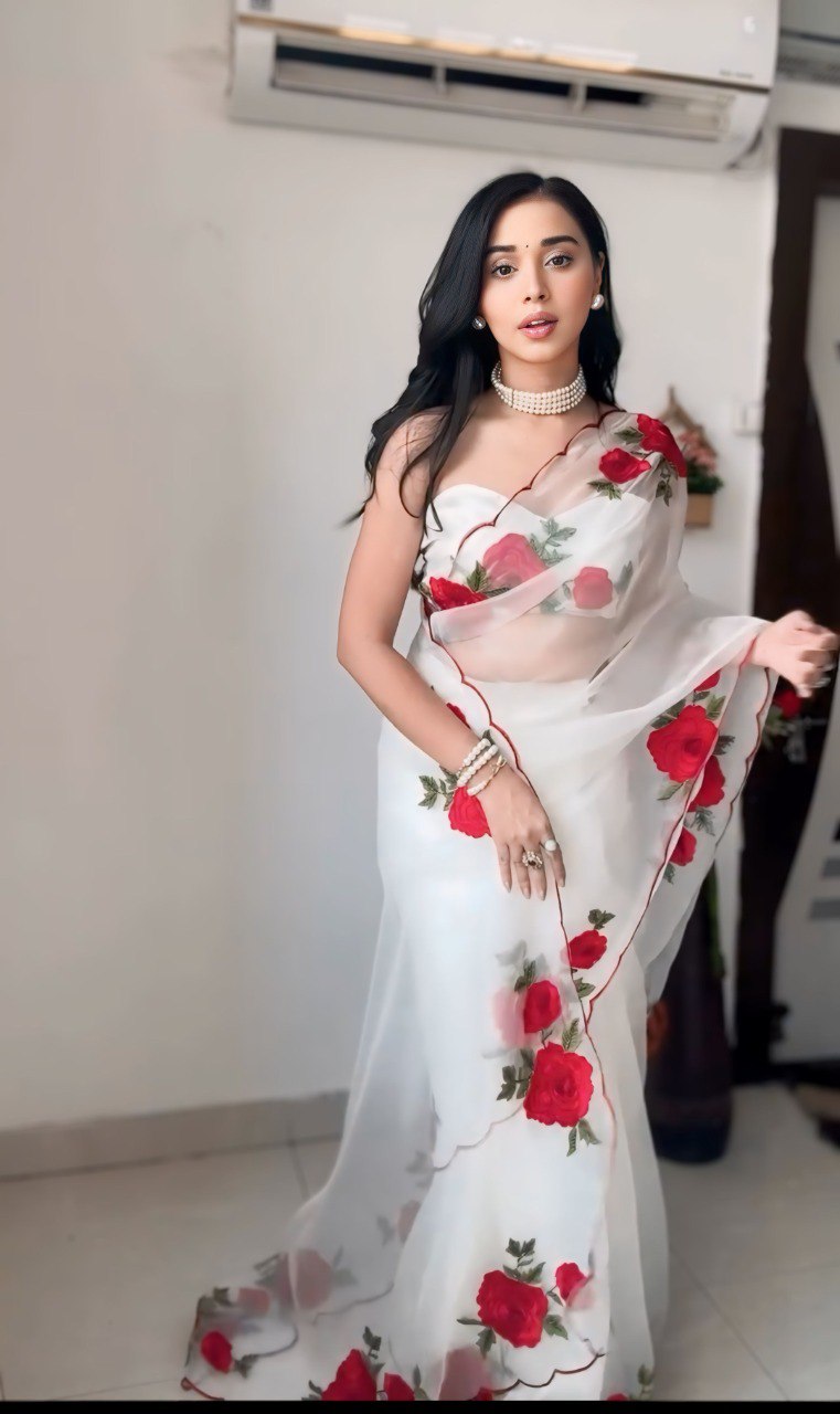 Woman wearing a stylish, comfortable white saree with red roses; ethnic wear.