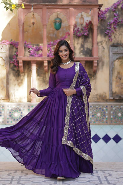 Woman in a purple flared gown with embroidered dupatta, posing with a slight smile.