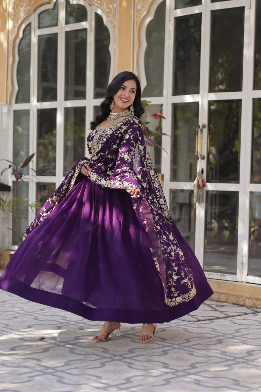 Models in purple and pink premium embroidered Indian gowns holding hands.
