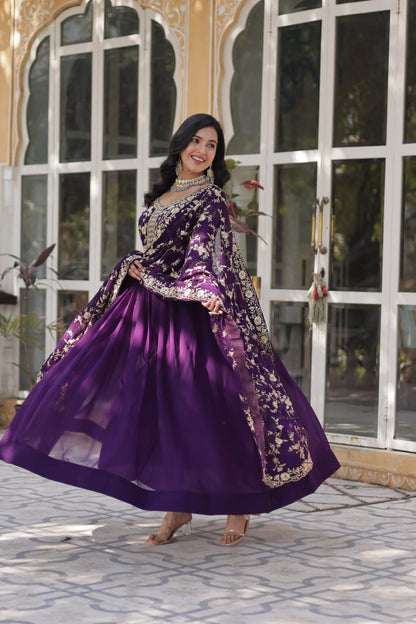 Models in purple and pink premium embroidered Indian gowns holding hands.