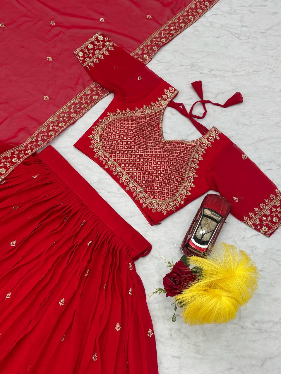 Close up of red choli, lehenga, and dupatta with gold embroidery.