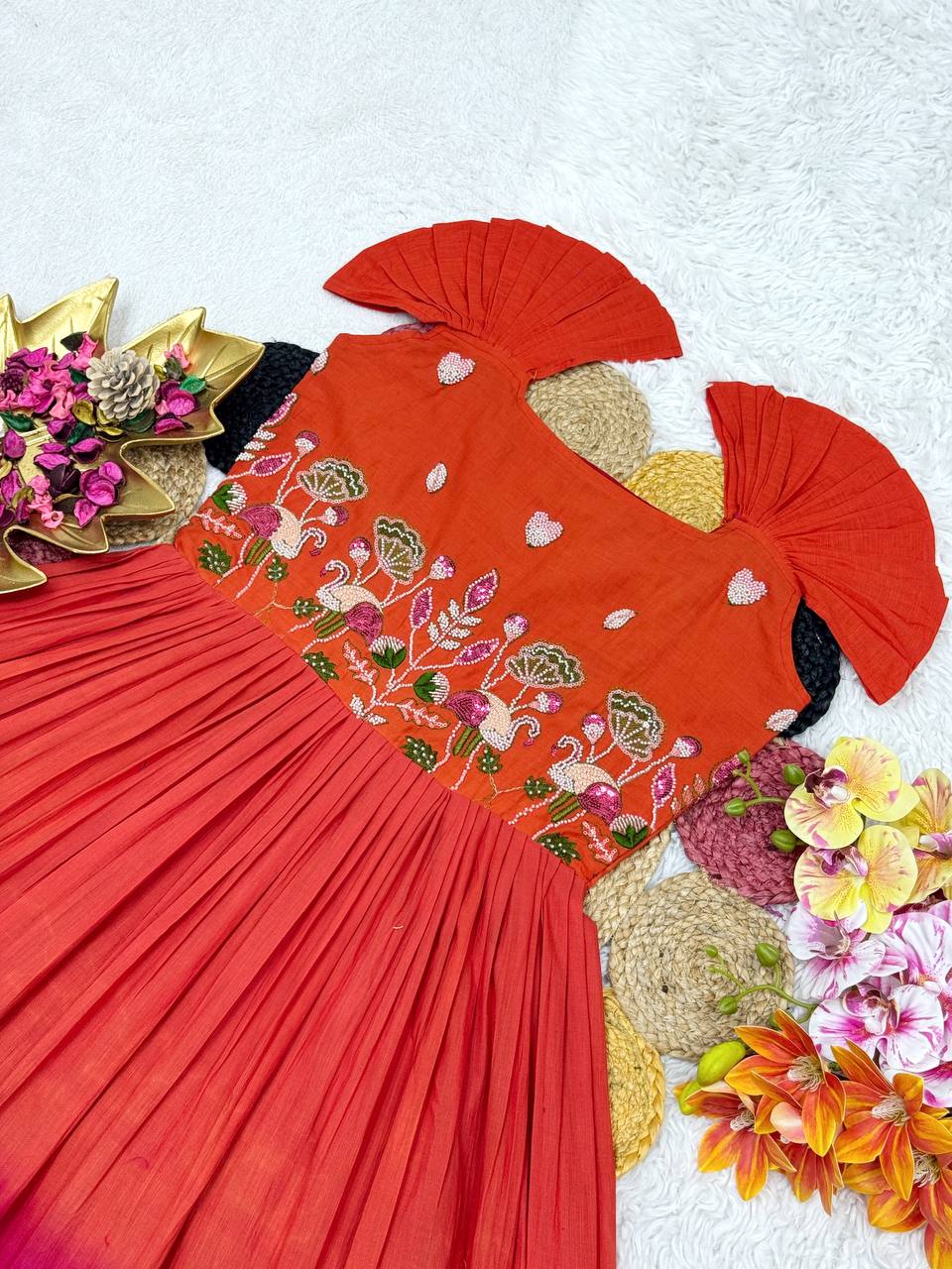 Detailed view of the orange and pink cotton gown with handwork, surrounded by decorative elements.