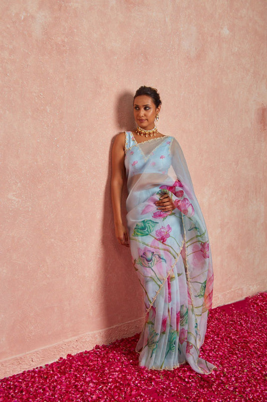 Woman wearing a light blue organza silk saree with pink floral prints.