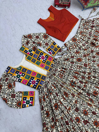 Flat lay of Kachchi Charm lehenga choli set showing orange blouse, mirror work shrug, and festive skirt.