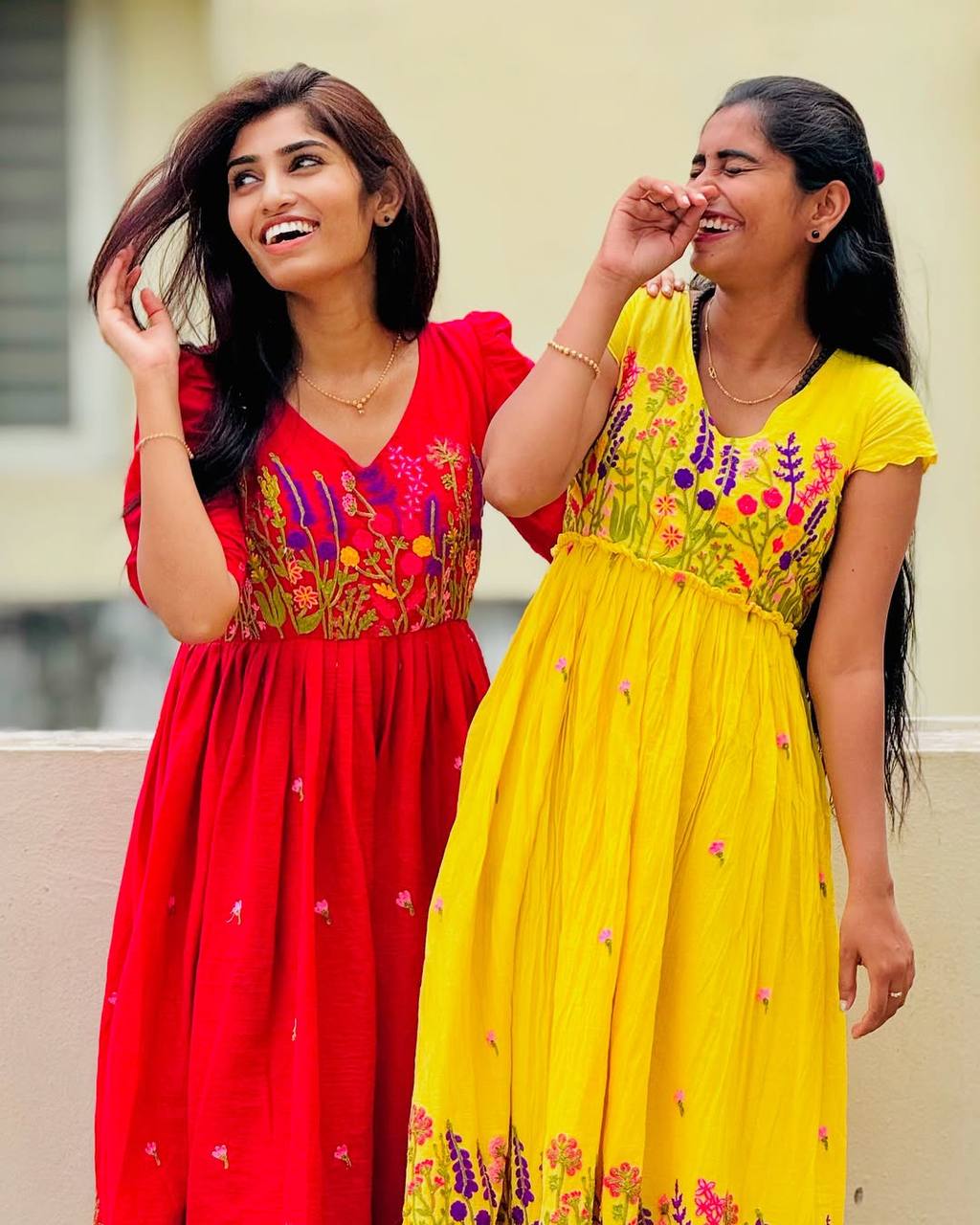 Women laughing in red and yellow embroidered Floral Embrace dresses by Rangbhoomi. Summer fashion.
