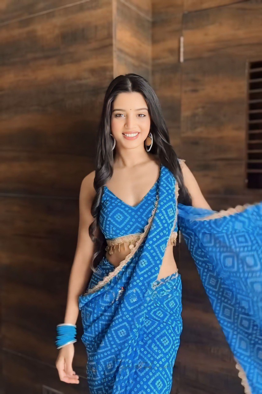 Model smiling and wearing a blue ready to wear saree with a geometric print.