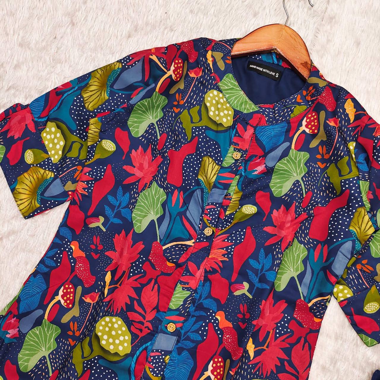 Close-up of Blue Forest Kurti fabric with bold multicolor floral and wooden buttons.