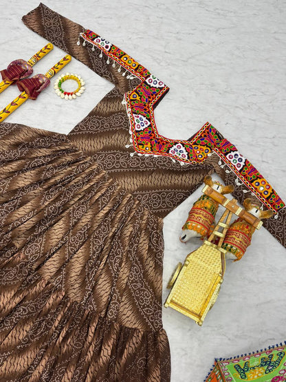 Brown Bandhni Gamathi work gown flat lay, with mirror work yoke and dandiya sticks for Navratri.