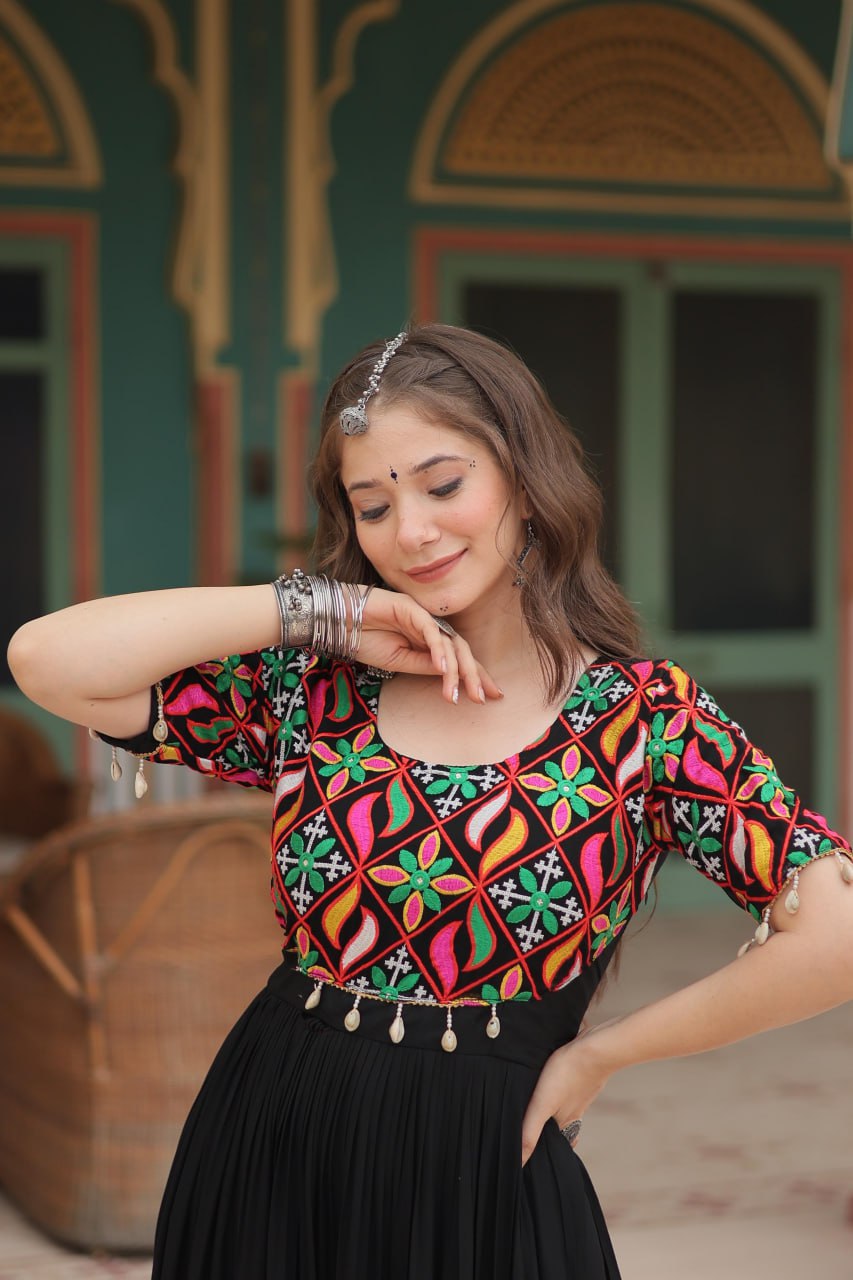 Woman in black boho Navratri gown, close-up of colorful Kutchi work bodice and festival jewelry.