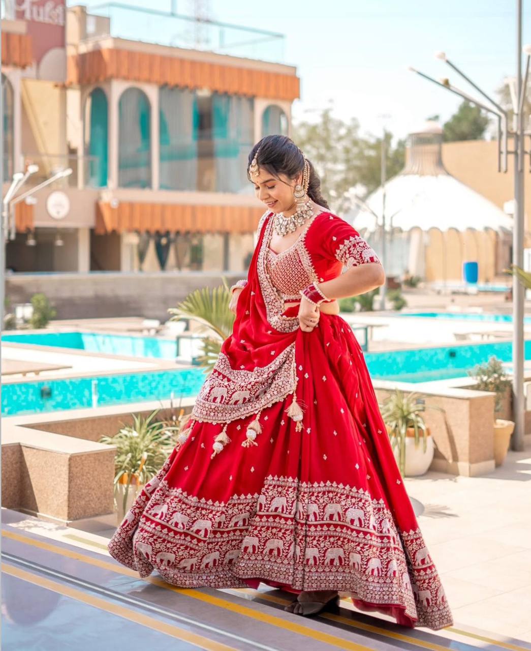 Woman walking in a red embroidered Rangbhoomi lehenga choli.