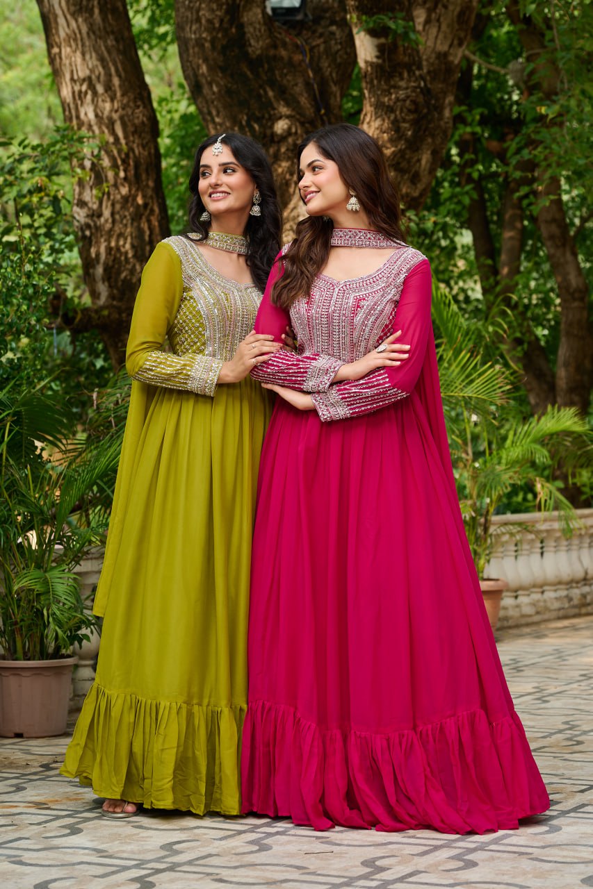Two women in colorful traditional dresses standing outdoors with greenery in the background