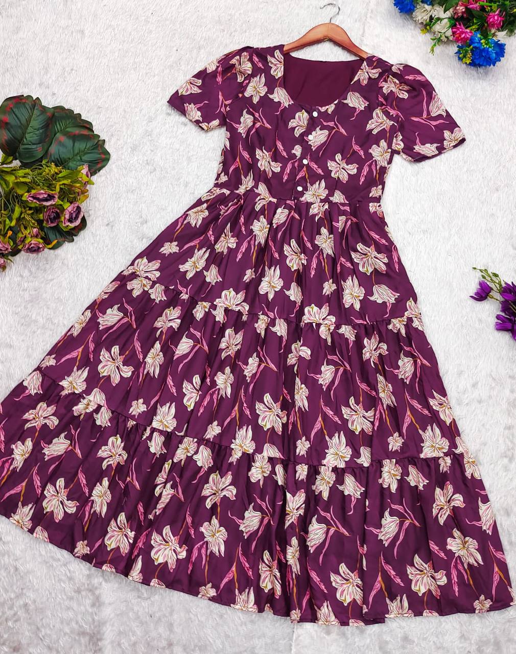 The Moringa Maxi dress in plum with floral print, laid flat. Shows the dress's tiered design and button details.