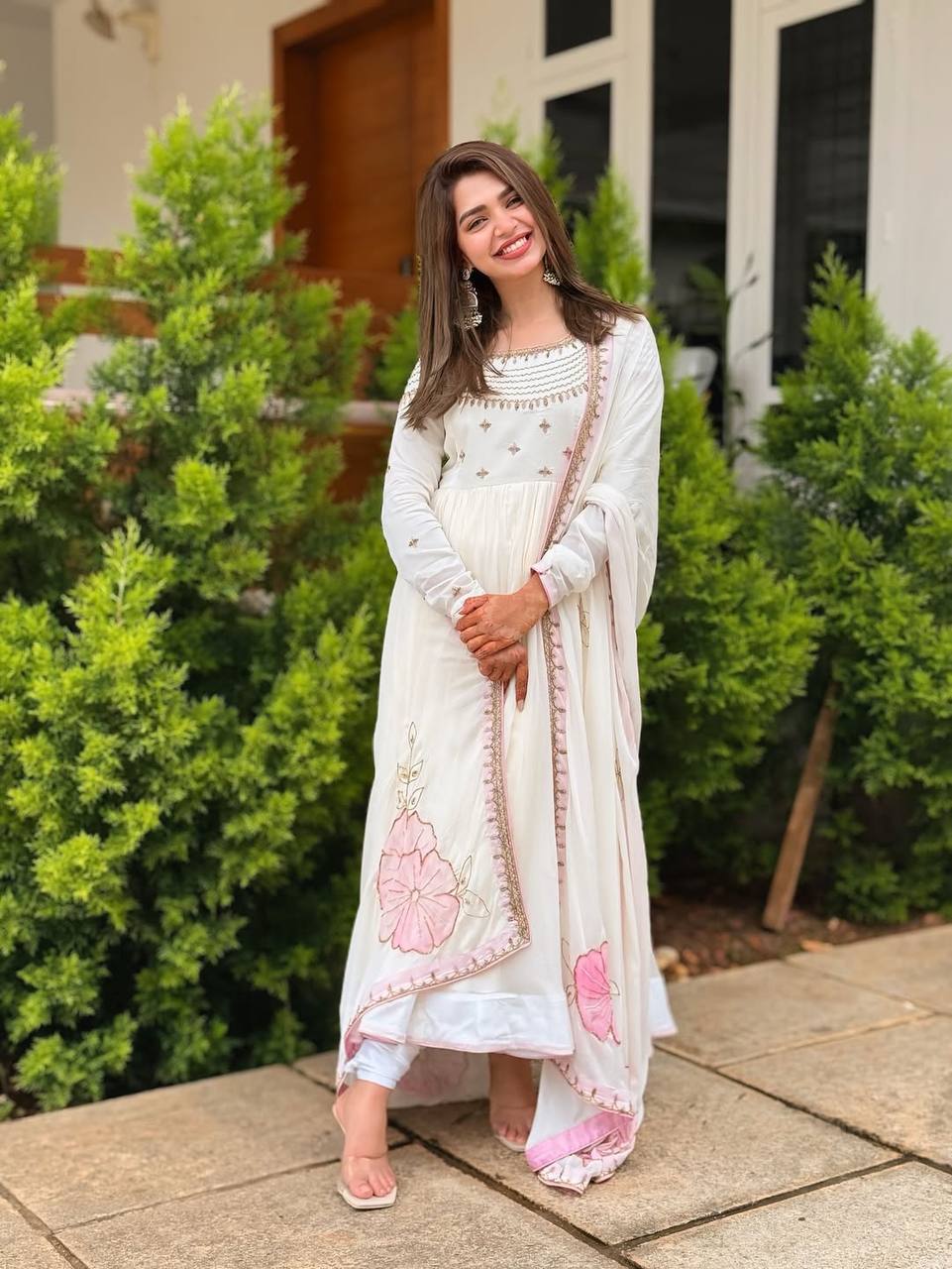 Woman outdoors in floor-length off-white gown with pink floral embroidered dupatta.