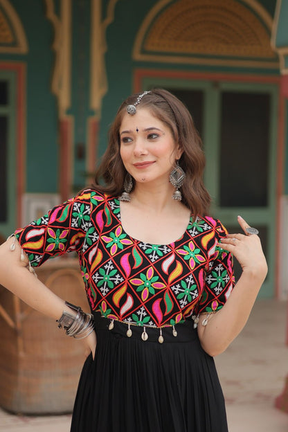 Close-up of vibrant Kutchi embroidery on black gown's bodice, woman accessorized for Navratri.
