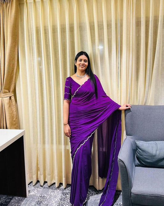 Model adjusts bracelet while wearing pre-stitched purple saree with silver border.