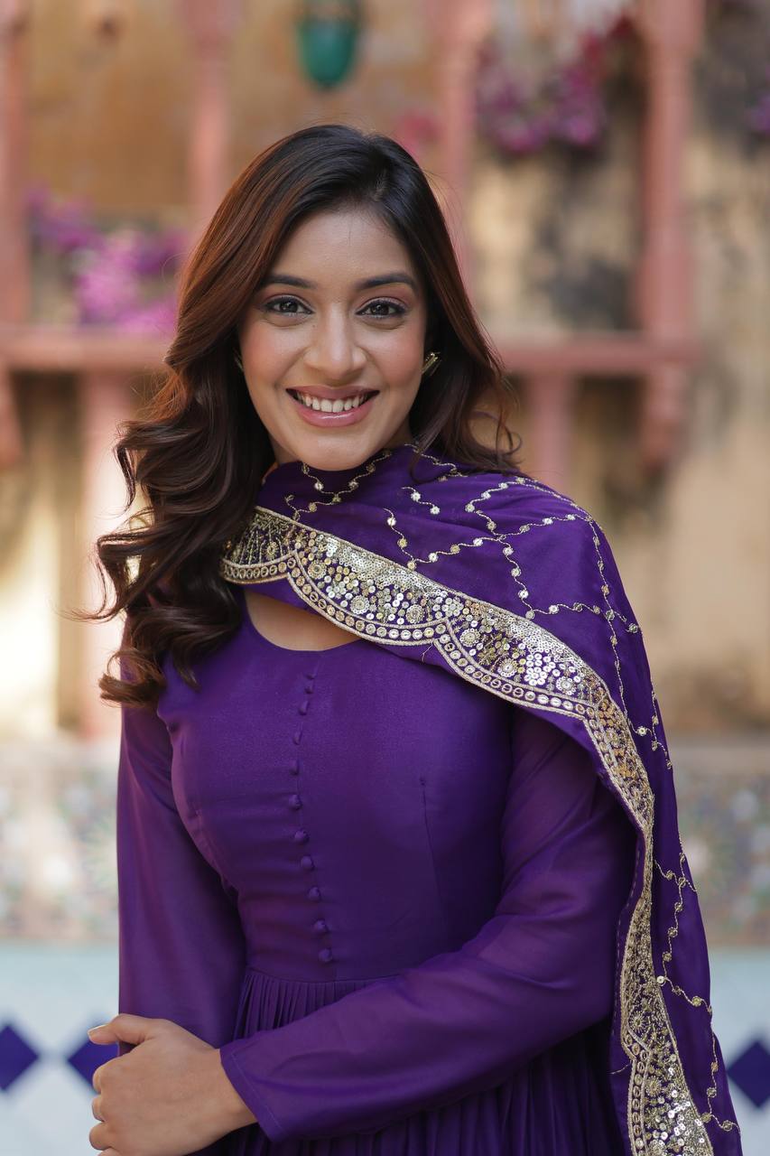 Close-up of woman smiling in a purple flared gown with a gold embroidered dupatta.