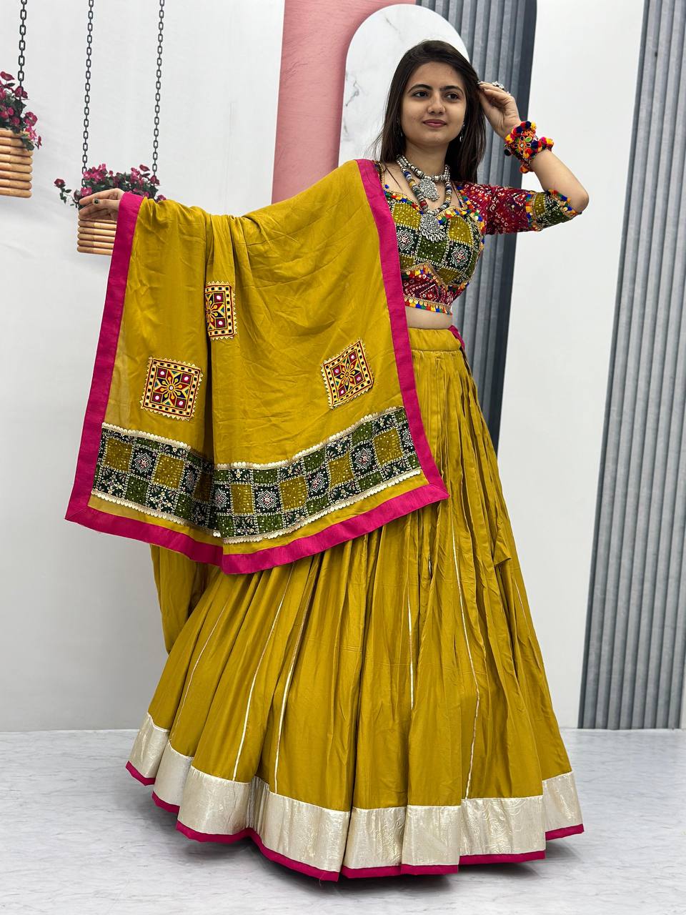Navratri lehenga choli in golden yellow, featuring detailed dupatta and ethnic jewelry.
