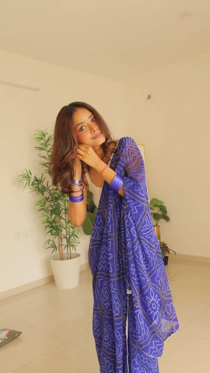 Woman in ready-to-wear blue georgette saree with white border, styled with a white top.
