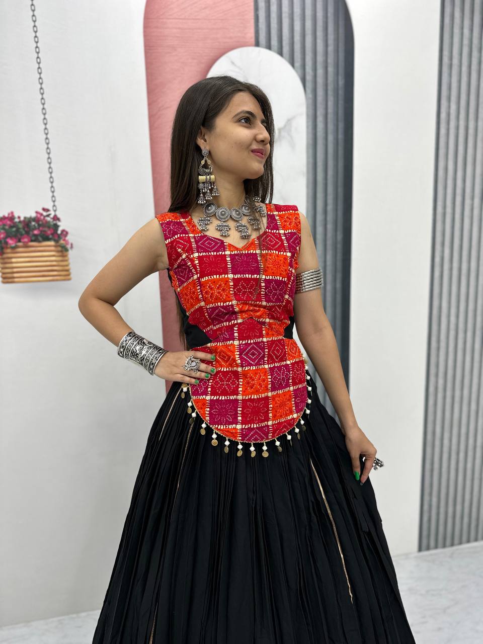 Close-up of red and orange patterned choli with shell lace detail and black lehenga, styled for Navratri.