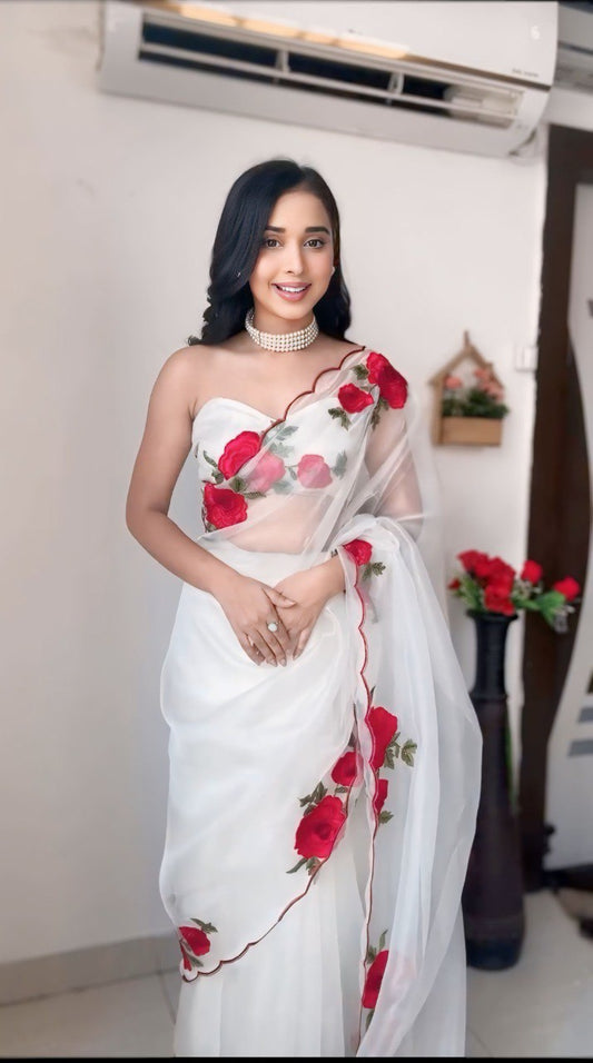 Elegant woman in white organza saree with romantic red rose prints.