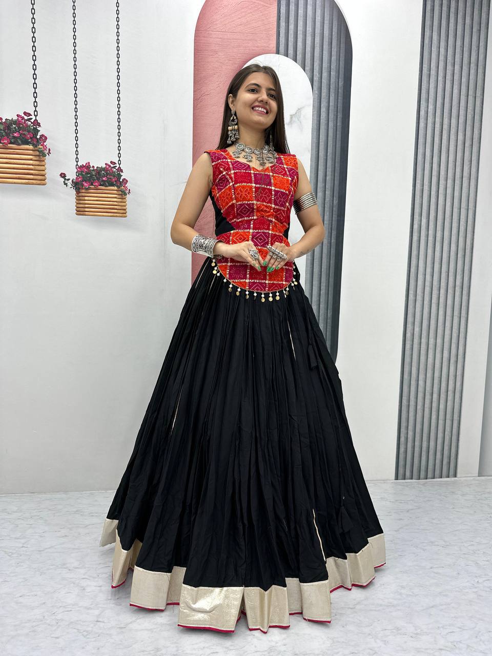 Woman wearing black pure cotton lehenga with gold border and vibrant red printed choli, ready for Navratri.