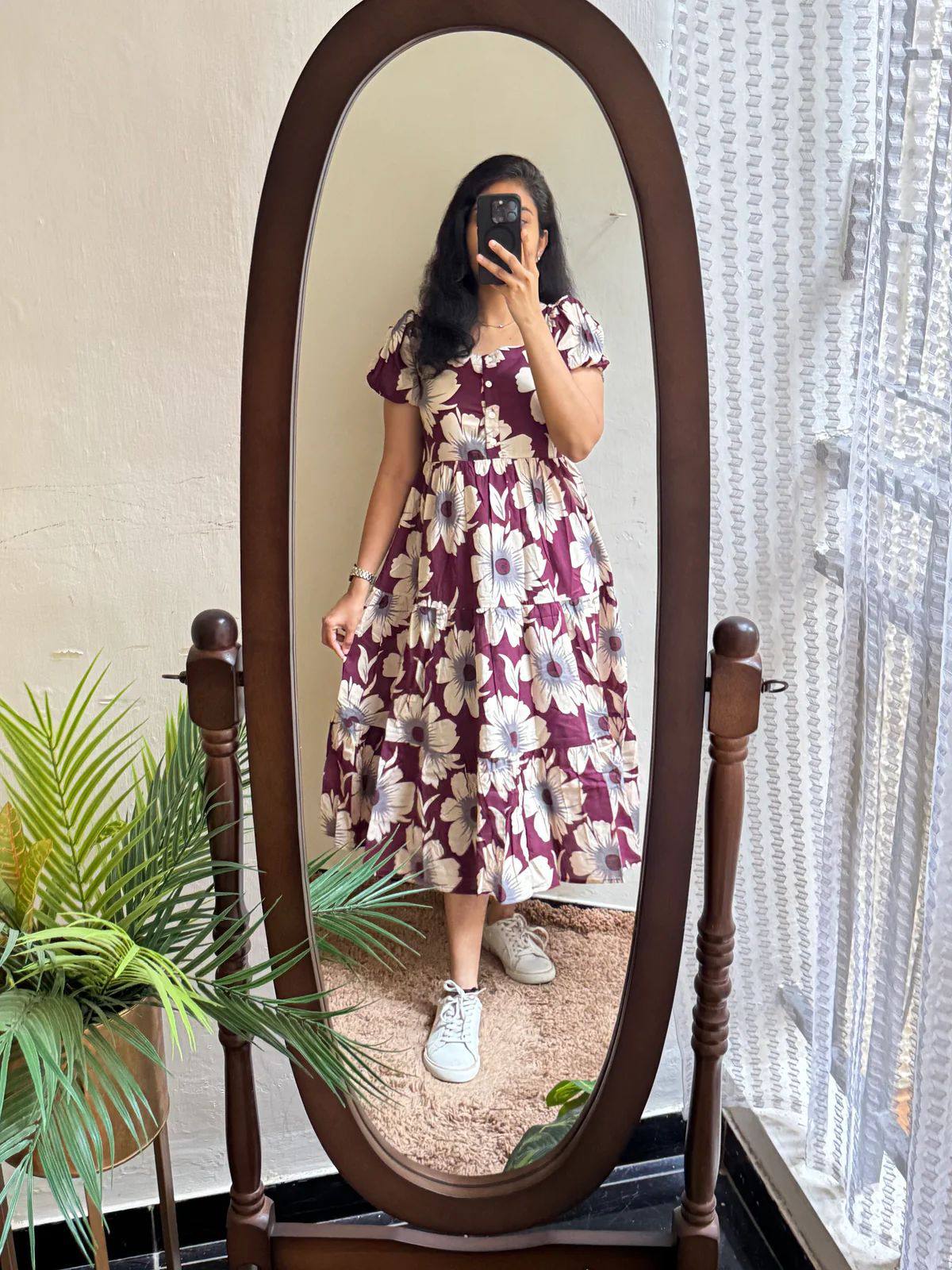 Mirror reflection of a woman wearing a floral maroon tiered maxi dress.