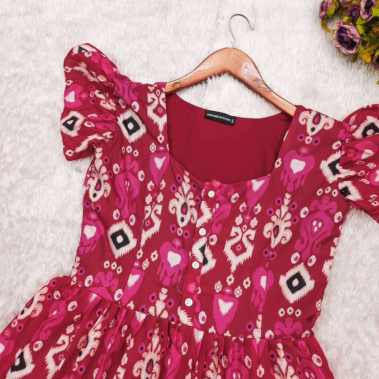 Dhano Maxi pink Patola dress on a hanger, showcasing the fabric and design.