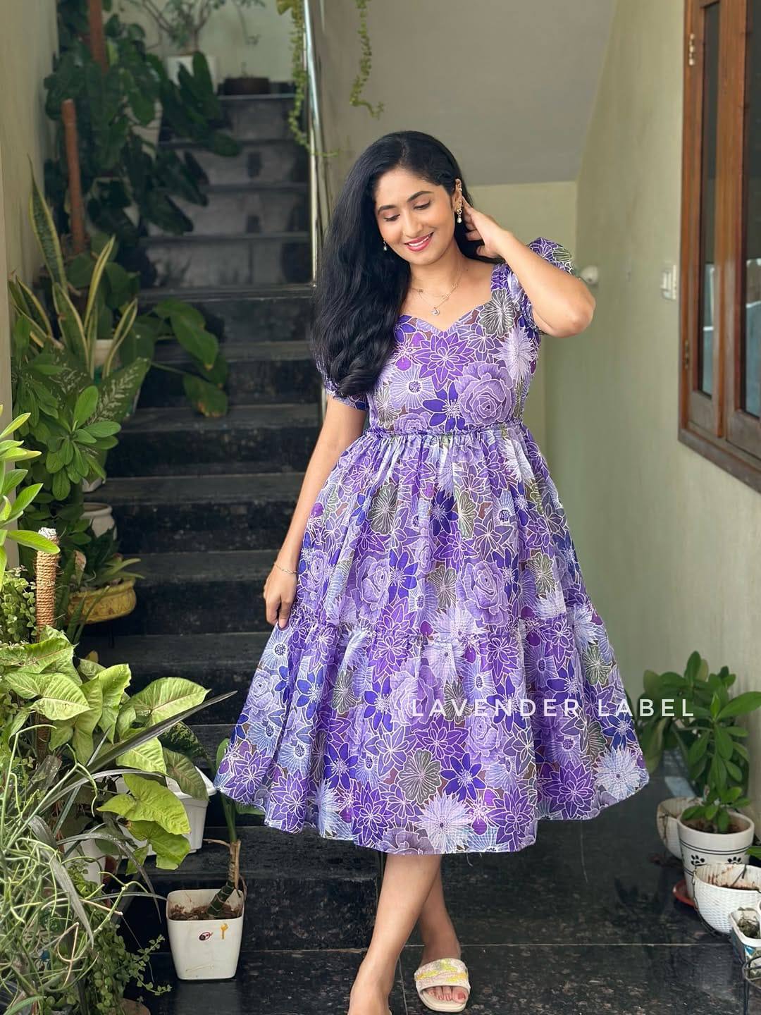 Charming woman in layered purple dress with floral pattern.