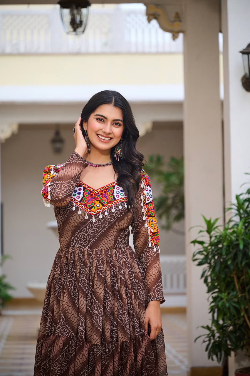 Model in brown Bandhni festive gown, showing off colorful embroidered yoke and ethnic earrings.