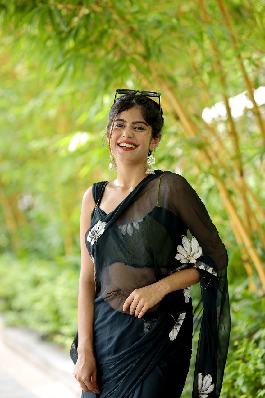 Close-up of a smiling model in a black floral georgette ready to wear saree.