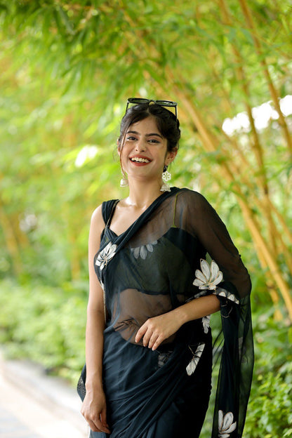 Close-up of a smiling model in a black floral georgette ready to wear saree.