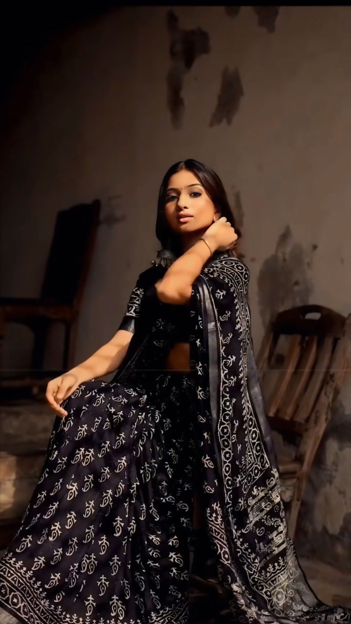 Woman in black & white printed ready-to-wear cotton saree sitting on steps.